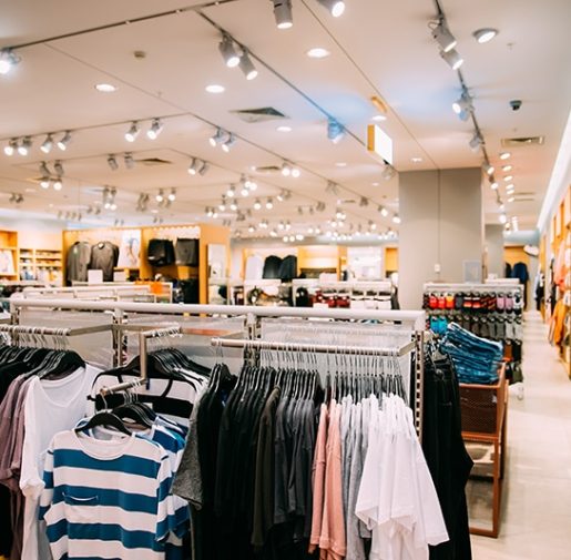 Colorful Bright Clothes On Shelves And Hanger In Store Of Shopping Center.